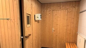 Una habitación con paneles de madera, un banco, una puerta y un termostato en la pared.