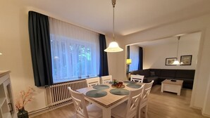 A dining area with a table and chairs, a sofa, and a radiator. - Am Museum - Holiday cottage Am Museum (Wyk auf Föhr)