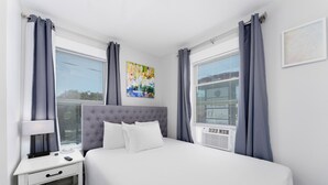 A bedroom with a bed, a bedside table, a lamp, and a window with curtains. - 2BDR+Extd Stay Discounts+Central+RemoteWork (Corpus Christi)