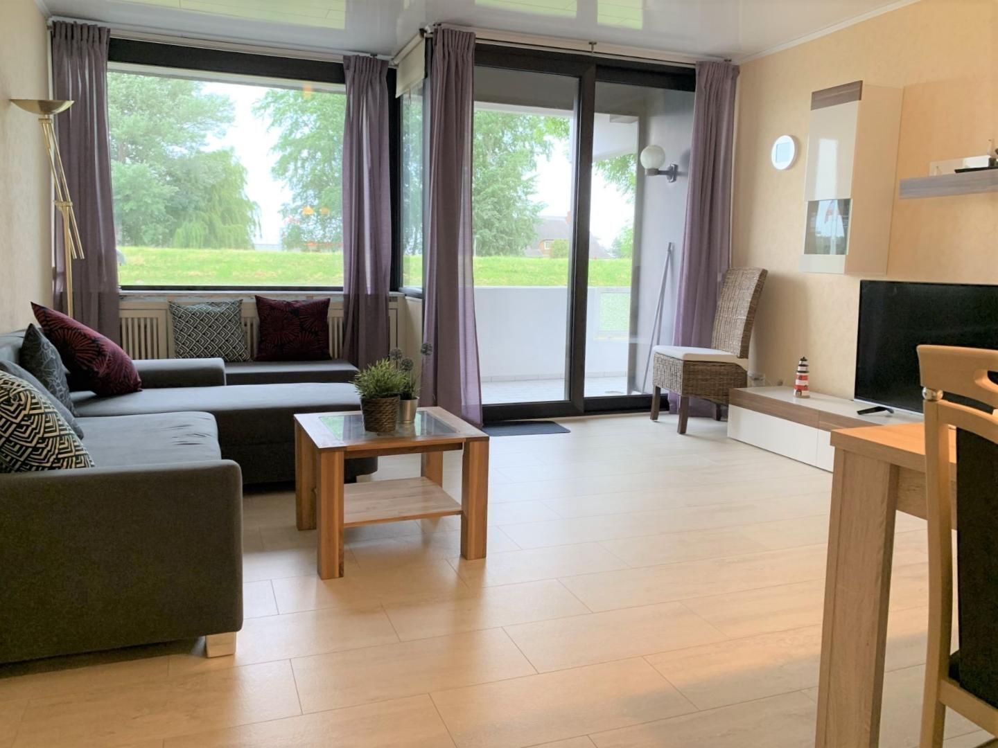 Ein modernes Wohnzimmer mit einer Couch, einem Holztisch und einem Fernseher.