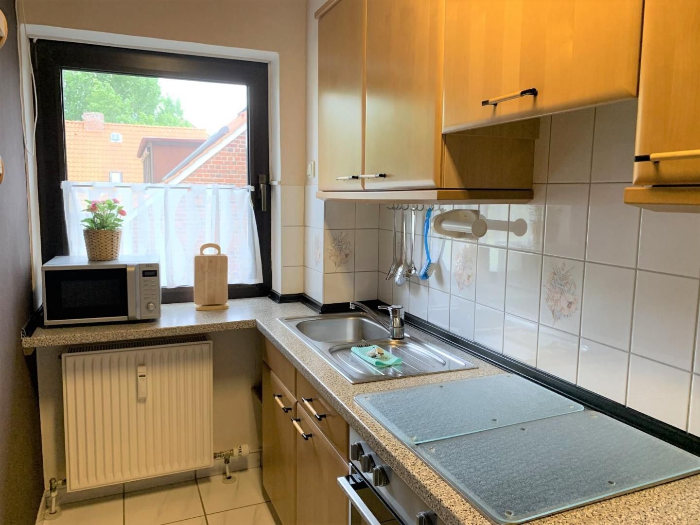 Una cocina compacta con ventana, microondas, fregadero y estufa.