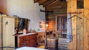 Una habitación rústica de madera con cama, cómoda de madera y pared de piedra.