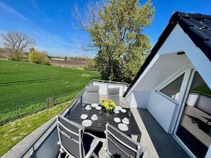 A dining area with a table set for four, overlooking a green field and a tree.