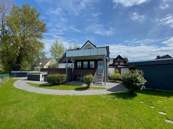 A modern two-story house with a covered patio and a small garden.