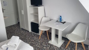 A hotel room with a bed, a white wardrobe, a television, a small table with chairs, and a water bottle. - Comfortable non-smoking apartment Die Remise Marengo RE-11 on Usedom - The (Stolpe auf Usedom)