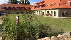 A large building with a red-tiled roof, multiple windows, and a well-maintained lawn in front. - Comfortable non-smoking apartment Die Remise Marengo RE-11 on Usedom - The (Stolpe auf Usedom)