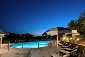 An outdoor swimming pool with lounge chairs and umbrellas, surrounded by a fence, under a night sky. - Beautiful private villa for 14 people with A/C, private pool, WIFI (Montecatini Terme)