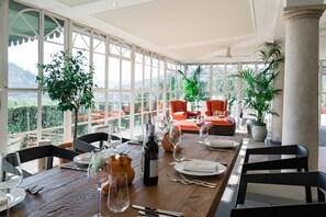 A dining area with a table set for four, large windows, and orange seating. - Beautiful private villa for 14 people with A/C, private pool, WIFI (Montecatini Terme)