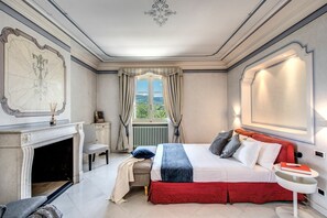 A bedroom with a fireplace, a bed with red and white bedding, a nightstand, and a view of the outdoors. - Beautiful private villa for 14 people with A/C, private pool, WIFI (Montecatini Terme)