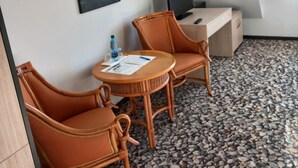 Une petite pièce accueillante, avec deux fauteuils en osier, une table ronde, un téléviseur et un tableau accroché au mur.