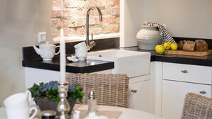 A modern kitchen with a brick wall, a sink, a tea set, and a fruit basket. - Die Remise Lexington RE-03 Holiday apartment with terrace on Usedom - Die Remise (Stolpe auf Usedom)
