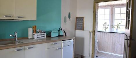 A kitchen with a sink, dishwasher, and a window with a view of the outside.