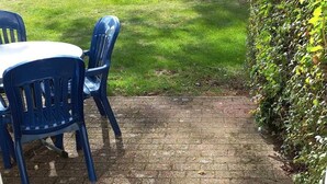 A patio area with a brick floor and a table with blue chairs.
