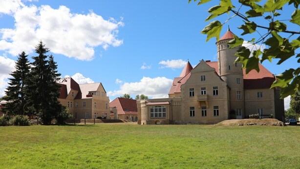 A large, historic building with multiple towers and a central courtyard.