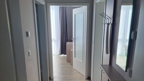 A hallway with wooden flooring, a door on the left, and a door on the right.