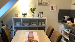 Une cuisine moderne avec un coin repas, comprenant une table en bois avec un set de table, des chaises et un plat de fruits.