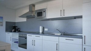 Une cuisine moderne dotée d’appareils électroménagers en acier inoxydable, de meubles blancs et d’un four encastré.