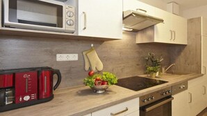 A modern kitchen with a microwave, coffee maker, and a bowl of fresh vegetables on the counter. - Cozy vacation apartment Landhof Schwalbennest LH-204 quiet village location on Usedom (Stolpe auf Usedom)
