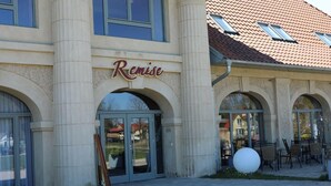 A building with the sign 'Remise' above the entrance, featuring large glass doors and arched windows. - Cozy vacation apartment Landhof Schwalbennest LH-204 quiet village location on Usedom (Stolpe auf Usedom)