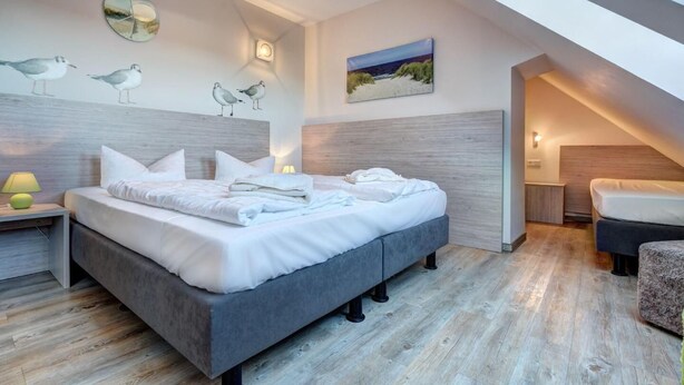 Een moderne slaapkamer met een groot bed, een nachtkastje, een lamp en een schilderij aan de muur.