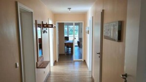 A hallway with wooden flooring, white walls, and a door leading to a dining area. - Cozy vacation apartment Landhof Weide LH-202 in a quiet village idyll on Usedom - (Stolpe auf Usedom)