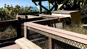 Una pasarela de madera con una mesa de picnic y un cartel.