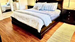 Un dormitorio con una cama grande, un aparador, una mesita de noche, un espejo y dos lámparas.