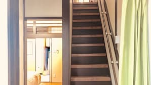 A staircase with wooden steps and metal handrails, leading to a room with a bed and a window.