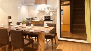A modern kitchen with a dining area, wooden furniture, and a view of a staircase.
