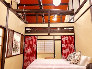 Una habitación al estilo japonés tradicional, con suelo de tatami, techo de madera bajo y puertas correderas shoji.