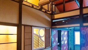 A traditional Japanese-style room with tatami flooring, shoji screens, and a futon bed.