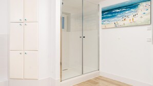 A room with a glass door leading to a shower area, a white wardrobe with star-shaped handles, and a beach scene painting on the wall. - Erika - House Erika, Germany (Sylt)