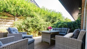 An outdoor patio with wicker furniture, a table, and a vase of flowers. - Erika - House Erika, Germany (Sylt)