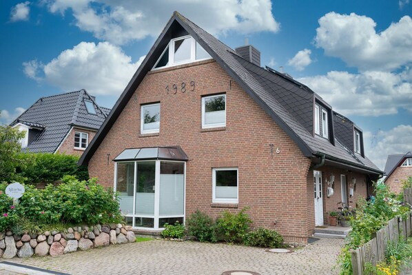 A two-story brick house with a gabled roof, a bay window, and a small porch. - Erika - House Erika, Germany (Sylt)