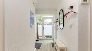 A hallway with a bench, a door leading outside, and a wall-mounted mirror. - Driftwood - House Driftwood (Sylt)