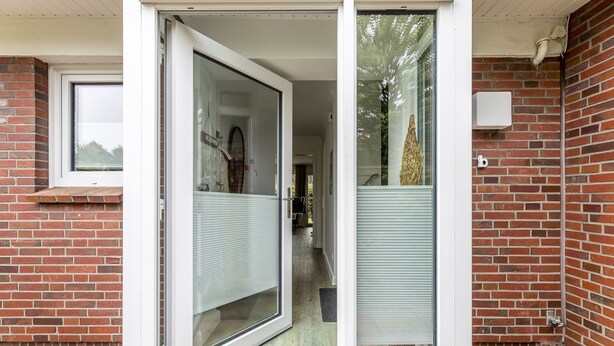 A modern building entrance with a glass door and a brick wall. - Driftwood - House Driftwood (Sylt)