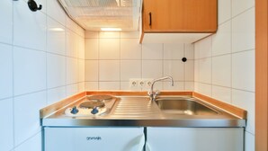 Une cuisine avec des carreaux blancs, une hotte de cuisine Bosch, un évier avec un robinet et des armoires en bois.