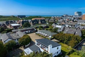 Vue aérienne d’un quartier résidentiel avec des maisons, un parking et une vue sur la mer.
