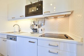 A modern kitchen with white cabinetry, a built-in microwave, a coffee maker, and a gas stove. - Appartement Auszeit, Deutschland (Wenningstedt-Braderup (Sylt))