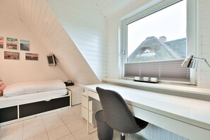 Habitación tipo dormitorio con cama, escritorio y ventana con vistas a una zona residencial.