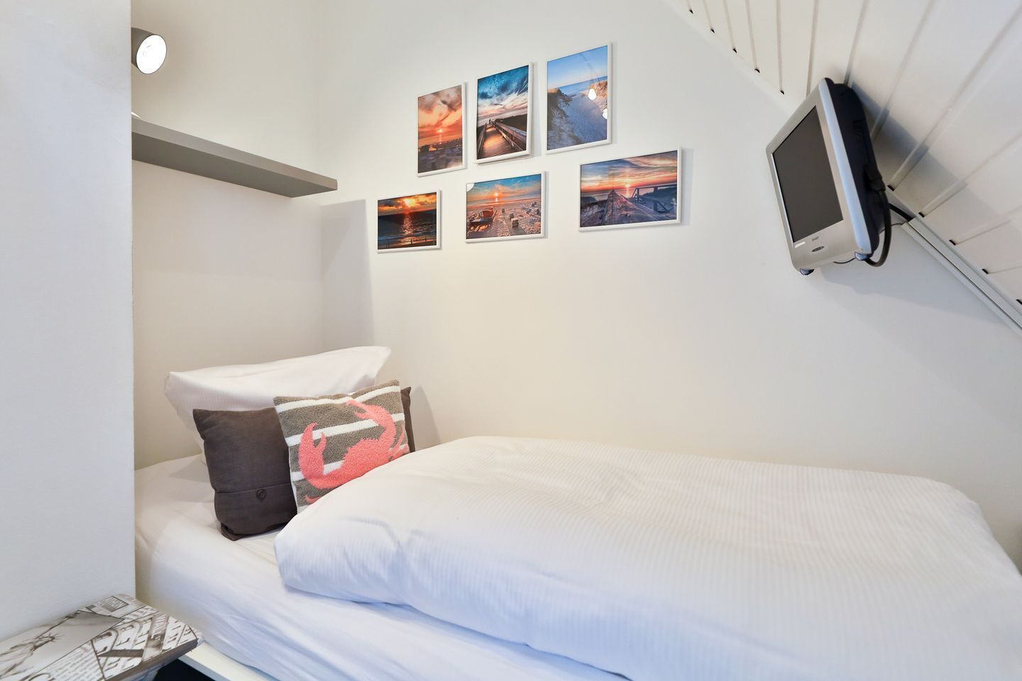 A bedroom with a bed, pillows, and a wall-mounted TV.