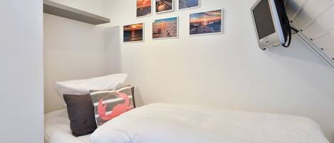 A bedroom with a bed, pillows, and a wall-mounted TV.
