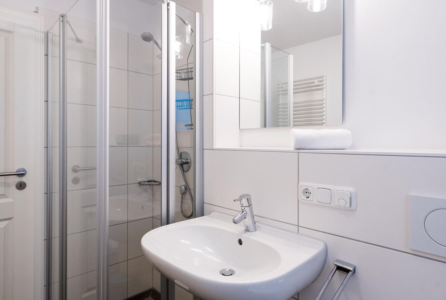 A modern bathroom with a glass shower enclosure, a white sink, and a mirror above the sink.