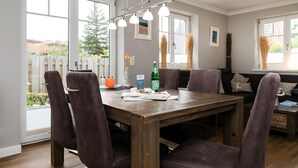 A dining area with a wooden table, four chairs, and a chandelier. - Lille Kamp 1, Germany (Sylt-Ost)