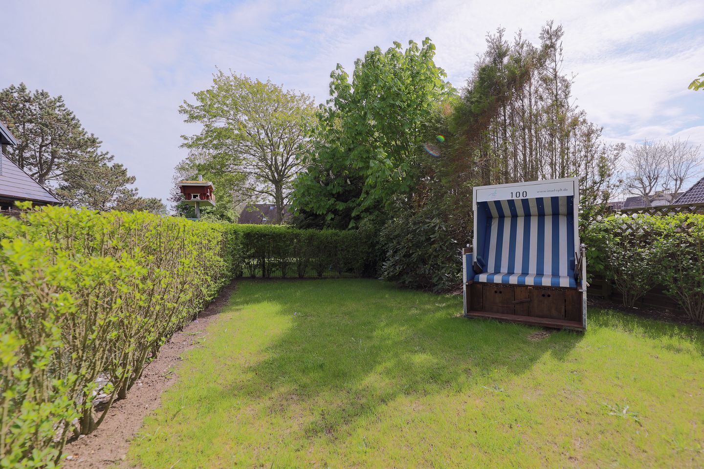 Un jardin avec une terrasse en bois et une chaise à rayures.