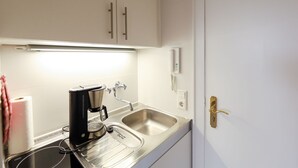 A kitchenette with a coffee maker, a sink, and a door with a brass handle. - Jasper - Hedighuis - Jasper in the Hedighuis (Sylt)