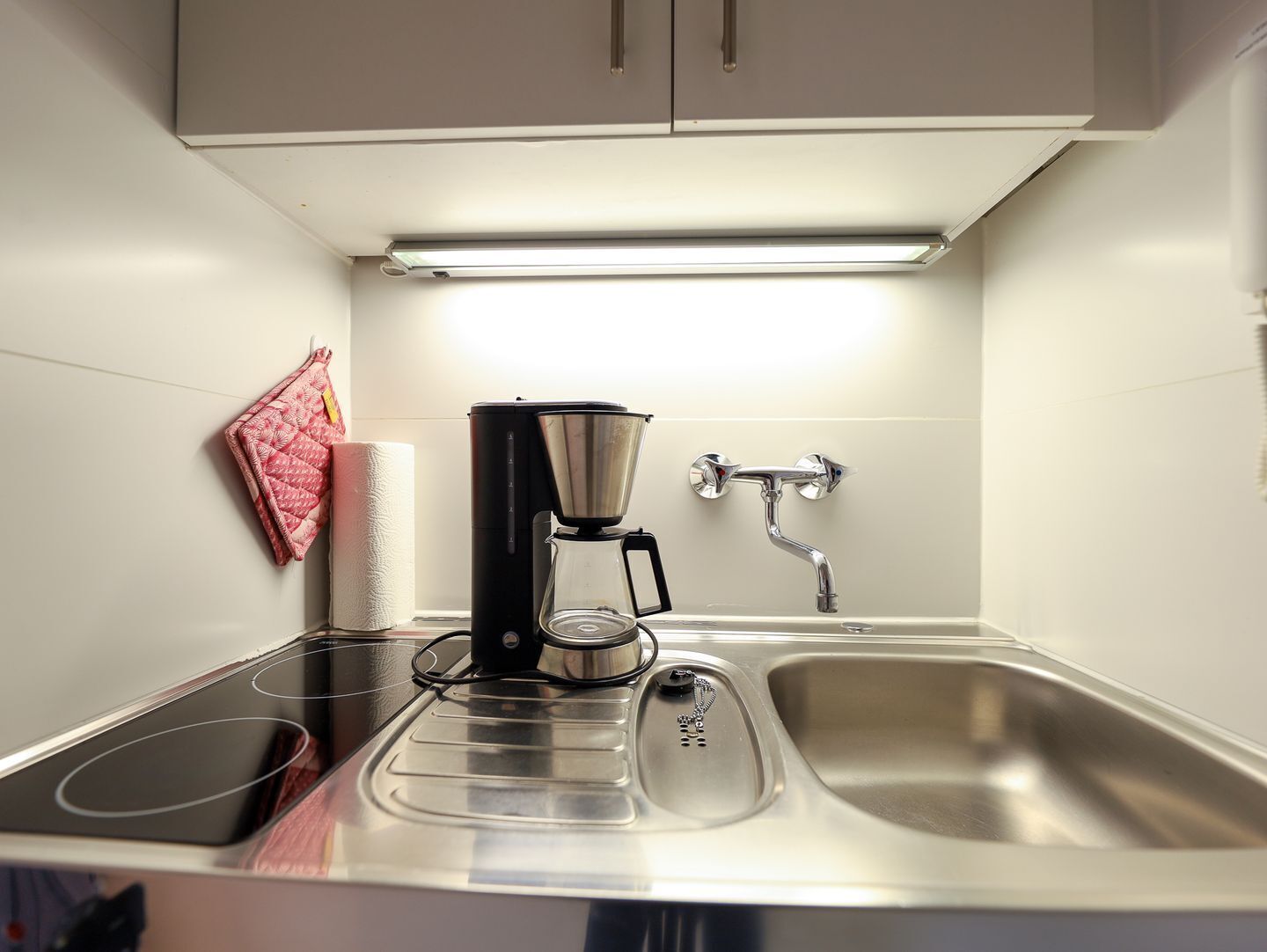 Une cuisine compacte équipée d’une machine à café, d’une bouilloire et d’un évier.