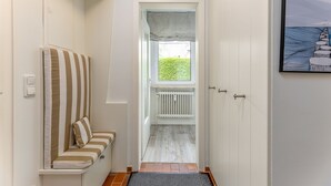 A narrow hallway with a bench on the left, a radiator in the center, and a door on the right.