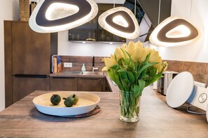 A modern kitchen with pendant lights, a fruit bowl, and a vase of flowers on the counter. - Appartement Emhüs, Deutschland (Sylt)