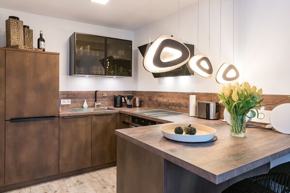 Eine moderne Küche mit Holzausstattung, einer eingebauten Mikrowelle, einer Kaffeemaschine und einem Toaster.